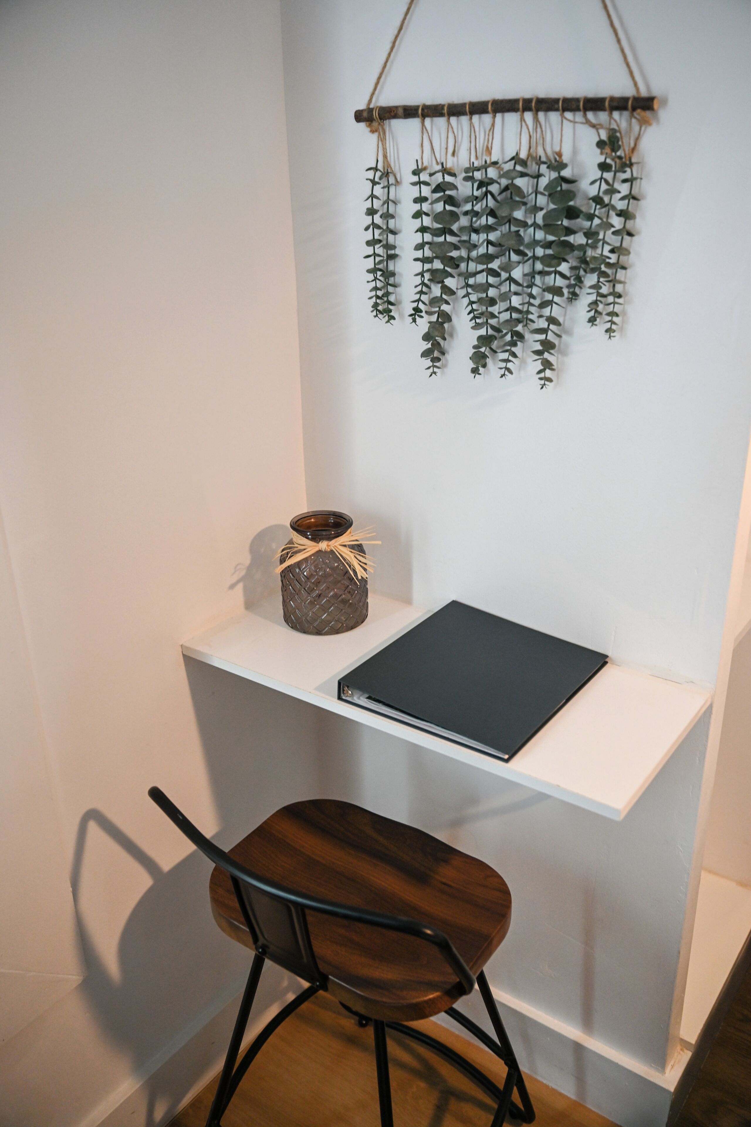 A small workspace with a desk, chair, and hanging plant.