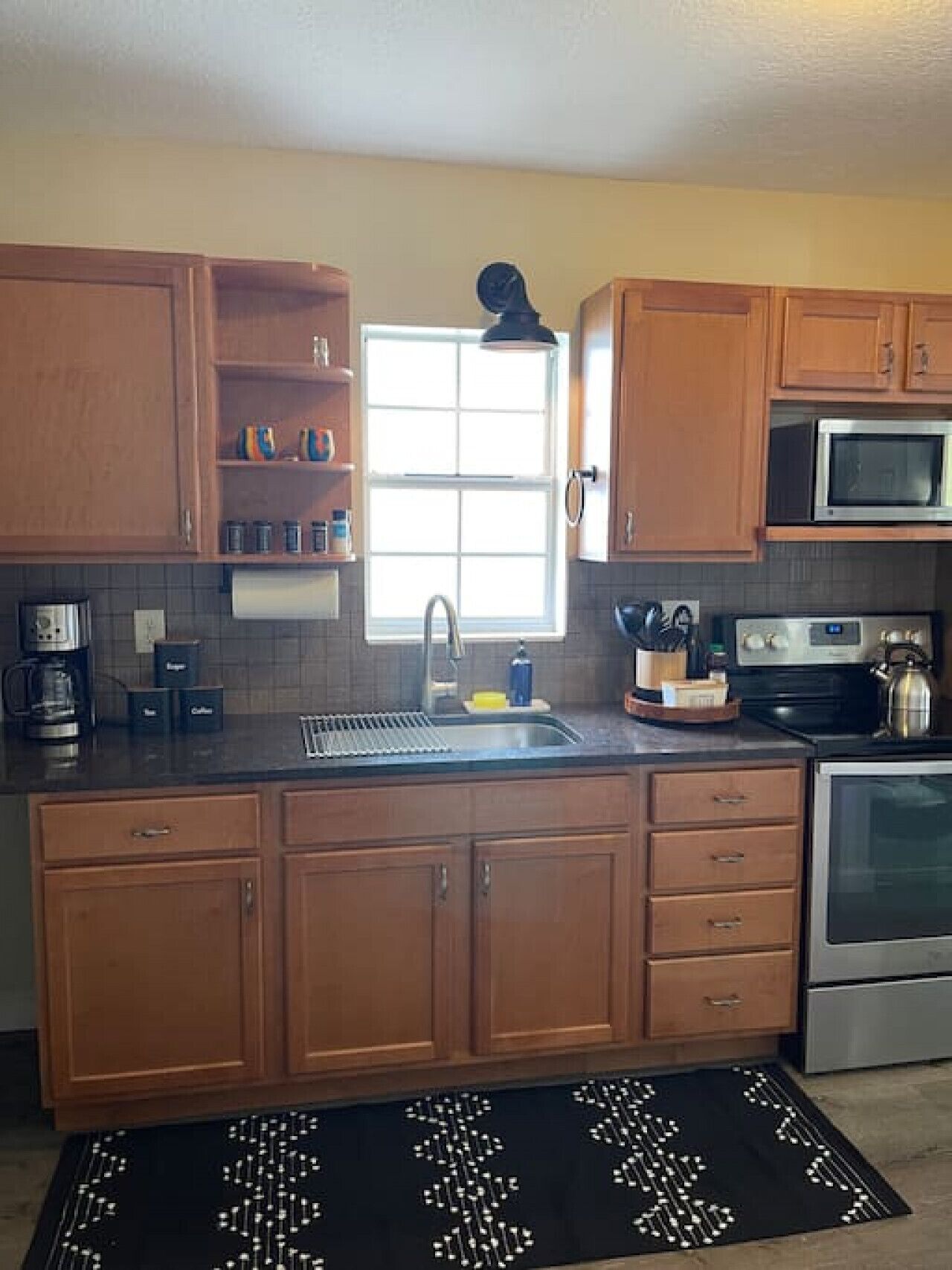 A kitchen with wooden cabinets, a stainless steel microwave, and a coffee maker.