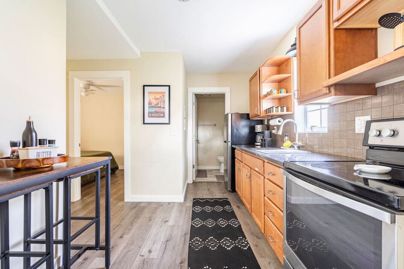 A modern kitchen with wooden cabinets, a black countertop, and a stainless steel stove.