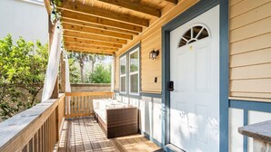 A covered porch with a wooden bench, a door with a number, and a window. - Cozy Getaway Steps from Historic Downtown with Parking (St. Augustine)