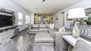Una sala de estar moderna con un sofá modular, un reposapiés y un televisor de pantalla plana.