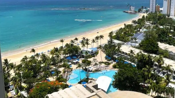 Een strandhotel met zwembad, strand en uitzicht op de oceaan.