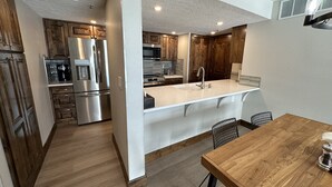 Una cocina moderna con electrodomésticos de acero inoxidable, una mesa de comedor de madera y una isla blanca con pileta.