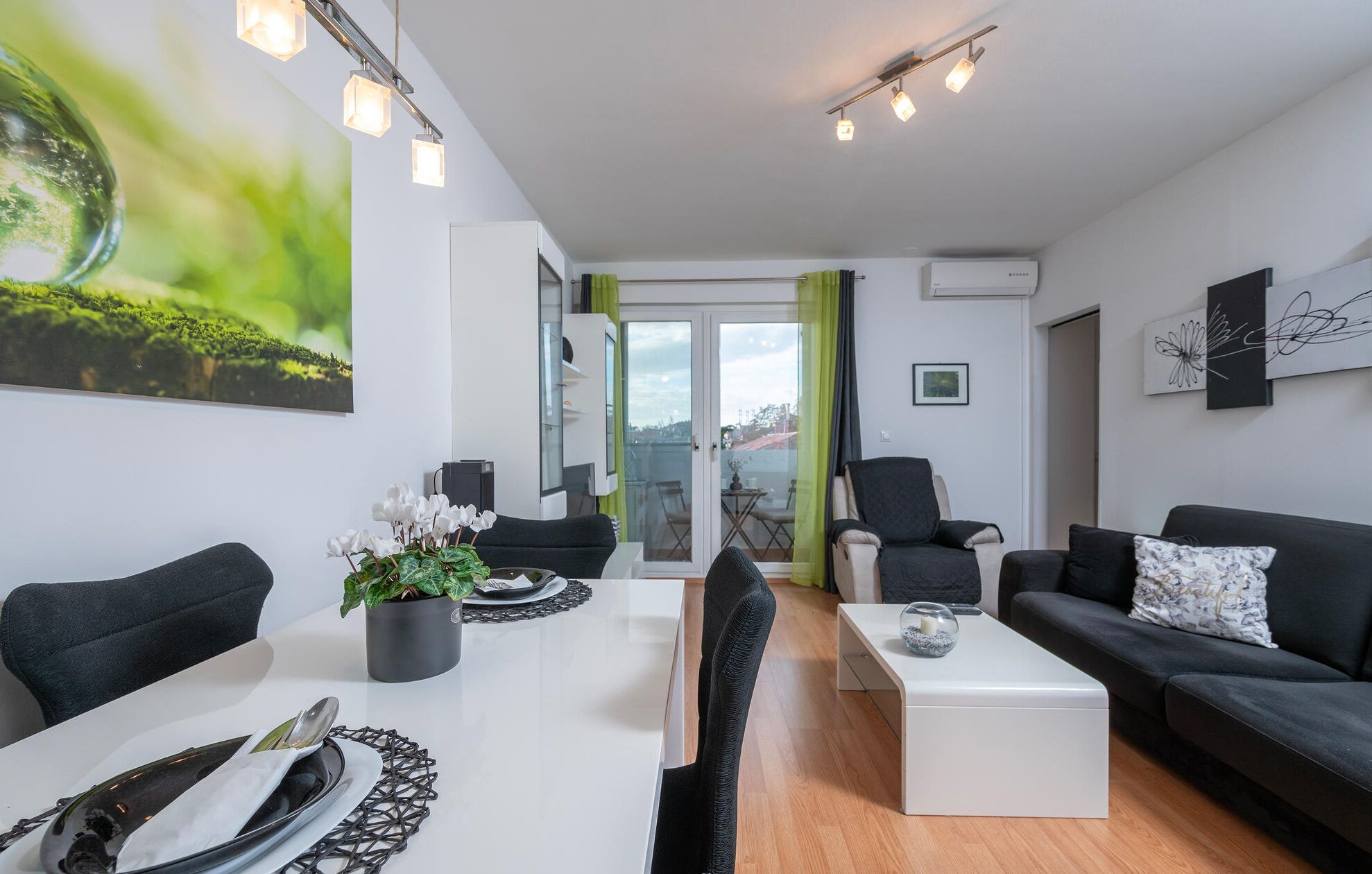 Un salon moderne avec un coin repas, comprenant un canapé, des fauteuils, une table basse et une table à manger pour deux personnes.