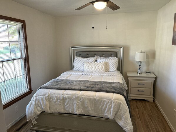Una camera da letto con un letto, un comodino, una lampada e una ventola a soffitto.