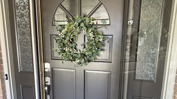A dark grey front door with a decorative wreath and a glass panel.