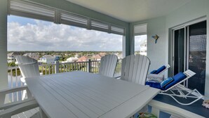 Ein Balkon mit Tisch und Stühlen, Blick auf Häuser, und ein blauer Sessel mit Kissen.