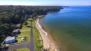 Ett flygbildsbild av ett kustområde med en strand, en väg och bostadshus.