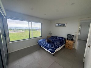 A bedroom with a bed, a window, a bedside table, and a fan.