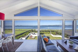 A modern living room with a large glass wall offering a view of the sea. - Beachside Long Beach (Long Beach)