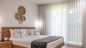 A bedroom with a wooden bed, white bedding, and a wall-mounted decorative item.