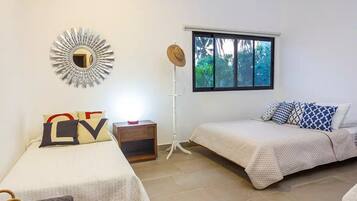 Un dormitorio con dos camas, un espejo, una ventana y una mesita de noche.