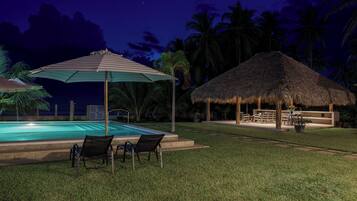 A pool area with lounge chairs and a thatched-roof structure.
