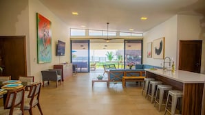 A spacious kitchen with a bar area, large windows, and a view of the outdoors.