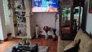 A living room with a television mounted on the wall, a sofa, a coffee table, and a cabinet with decorative items. - Nora's Laureles (Medellín)