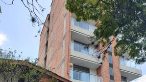 A multi-story building with a brick facade, balconies, and a gated entrance. - Nora's Laureles (Medellín)