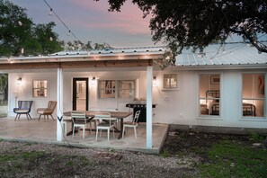 A house with a covered patio, a dining table with chairs, and a barbecue grill. - Casa Blanco (Wimberley)