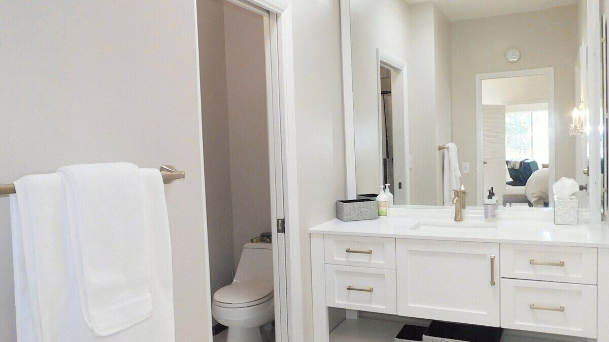 A bathroom with a white sink, mirror, and toilet.