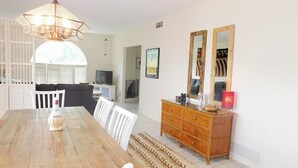 A dining area with a wooden table, white chairs, a wooden dresser, and a large mirror. - Avenida San Valle, Sabino Canyon (Tucson)