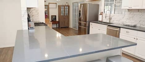 A modern kitchen with a central island, stainless steel appliances, and a view into the dining area.