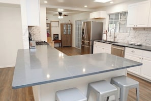 A modern kitchen with a central island, stainless steel appliances, and a view into the dining area. - Eclectic Oasis on Brown, Pet Friendly (Tucson)