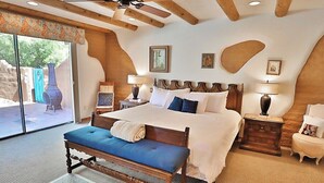Un dormitorio con una cama grande, un banco, dos mesitas de noche y un ventilador de techo.