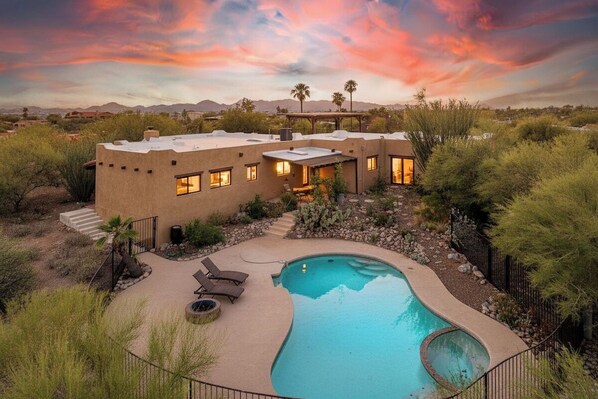 A house with a swimming pool, surrounded by desert vegetation.