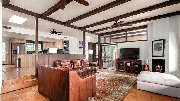 A spacious living area with a leather sofa, a white couch, and a patterned rug. - Foothills Beauty with Pool and Mountain Views (Tucson)