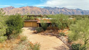 A desert landscape with mountains in the background, a covered patio area, and a well-maintained garden with various plants. - Foothills Beauty with Pool and Mountain Views (Tucson)