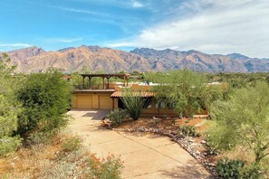 A desert landscape with mountains in the background, a covered patio area, and a well-maintained garden with various plants. - Foothills Beauty with Pool and Mountain Views (Tucson)