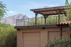 Een gebouw met een overdekt balkon, een garage en een bergachtig landschap op de achtergrond.