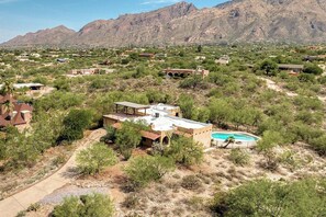 A residential area with houses, a swimming pool, and mountains in the background.