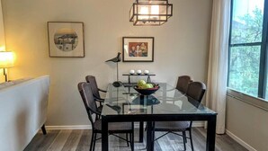 A dining area with a glass table, black chairs, a bird sculpture, and framed artwork on the wall. - Canyon View 26201 (Tucson)