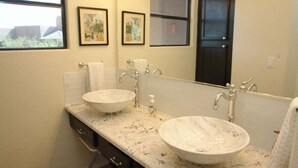 A bathroom with two sinks, a mirror, and framed pictures on the wall. - Canyon View 26201 (Tucson)