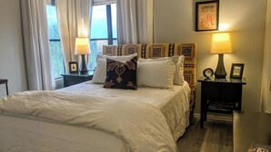 A neatly made bed with white bedding, a decorative pillow, and a bedside table with a lamp and a framed picture. - Canyon View 26201 (Tucson)