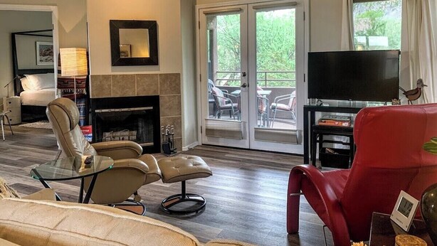 A living room with a fireplace, a television, and a red chair. - Canyon View 26201 (Tucson)