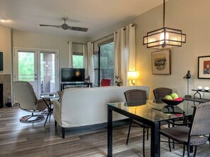 Uma sala de estar moderna com uma mesa de centro de vidro, um sofá e uma área de jantar com cadeiras.