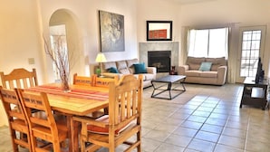 A living room with a fireplace, a sofa, a dining table with chairs, and a television. - West Side getaway Jacana Loop (Tucson)