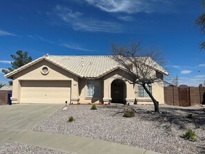 A single-story house with a garage, a small front yard with gravel, and a tree.