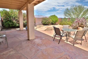 An outdoor patio with stone flooring, metal chairs, and a table.