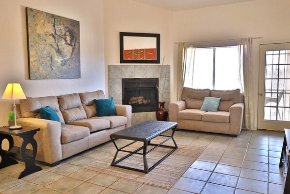 A living room with two sofas, a coffee table, a fireplace, and artwork on the walls.