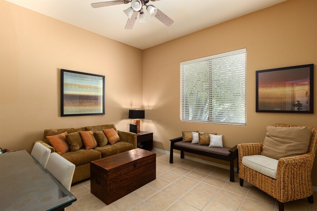 A living room with a sofa, armchair, coffee table, and a ceiling fan.