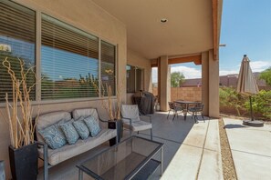 A covered patio area with a sofa, chairs, a table, and a grill. - Painted Feather - Modern Beauty with Pool and Spa (Tucson)