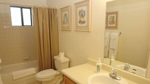 Ein Badezimmer mit Badewanne, Toilette, Waschbecken und einem großen Spiegel.