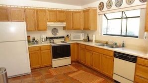 A kitchen with wooden cabinets, a stove, a microwave, and a dishwasher.