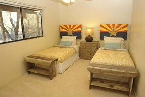 A bedroom with two single beds, a nightstand with a lamp, and two wall-mounted paintings. - Redington Hideaway with sweeping views (Tucson)