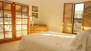 Ein Schlafzimmer mit einem Bett, einer Holzkommode und einem Fenster mit Jalousien.