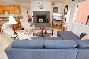 Un salon comprenant un canapé, une table basse en verre, une cheminée et un téléviseur.