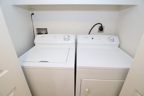 A laundry room with two stacked washers and dryers, a power outlet, and a control panel. - Condo 1111 at Ventana Vista (Tucson)