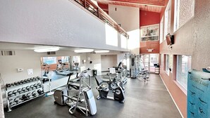 Une salle de sport à plusieurs niveaux, équipée de divers appareils d’exercice, notamment des tapis de course et des haltères.
